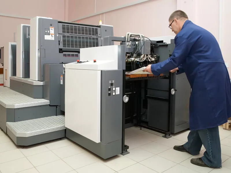 Büyük ticari baskı makinesini çalıştıran teknisyen